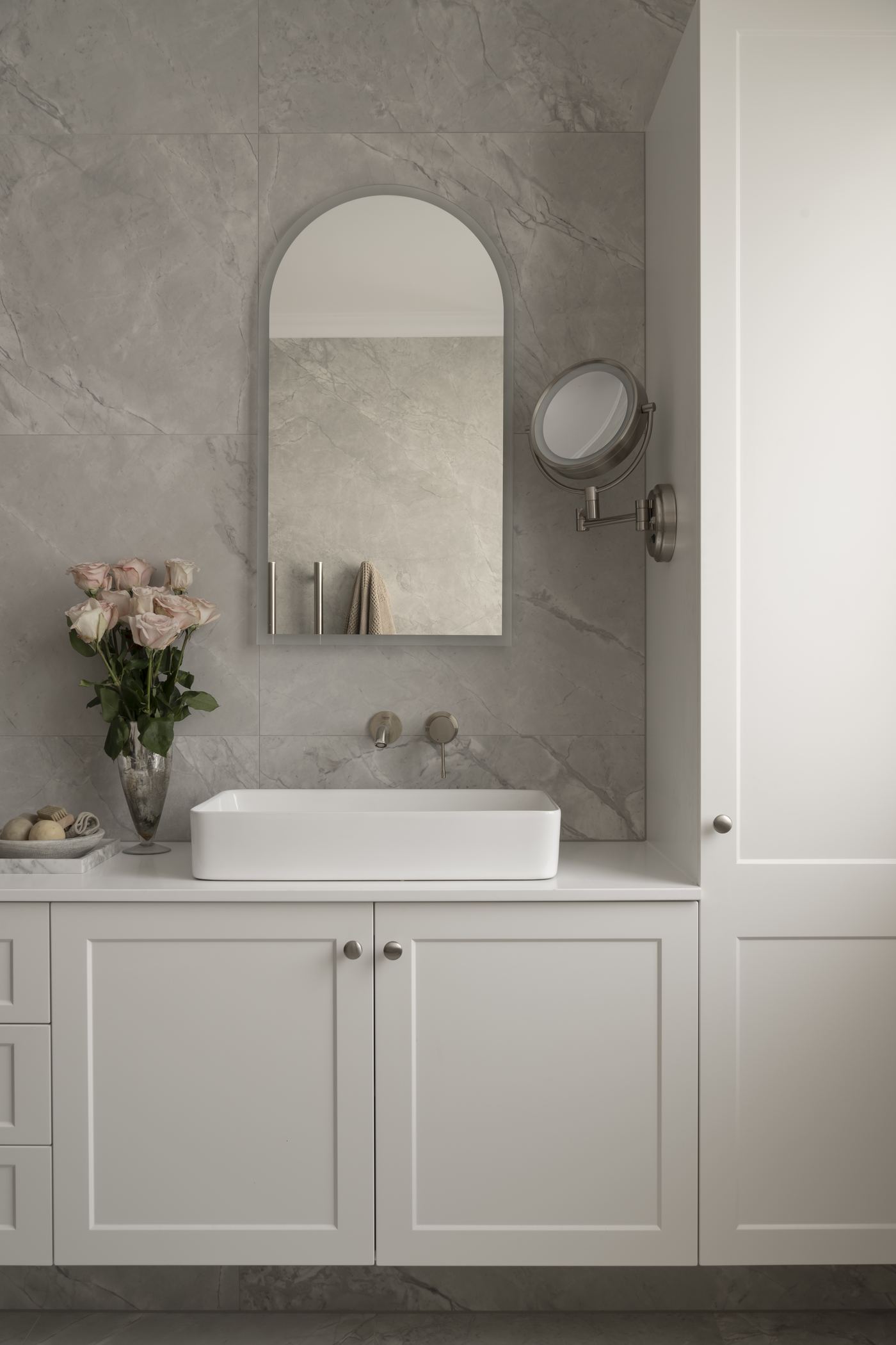 Stone-clad bathroom with arched mirror